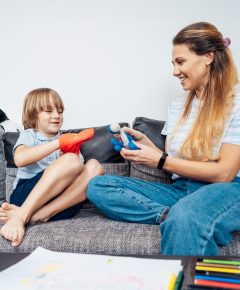 Happy mother and son playing role games with toys together in living room. Child psychotherapy process. Study in games and dialogs. Happy family. Young mother and son doing activities at home.